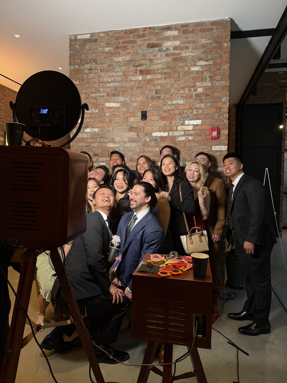 Wedding guests smiling at Snapbooth beside a table of colorful photo props