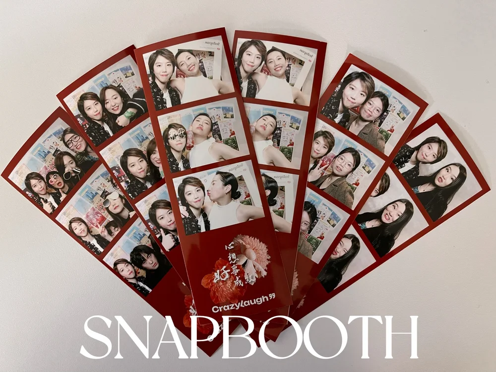 Friends laughing with props inside a vintage photo booth in NYC