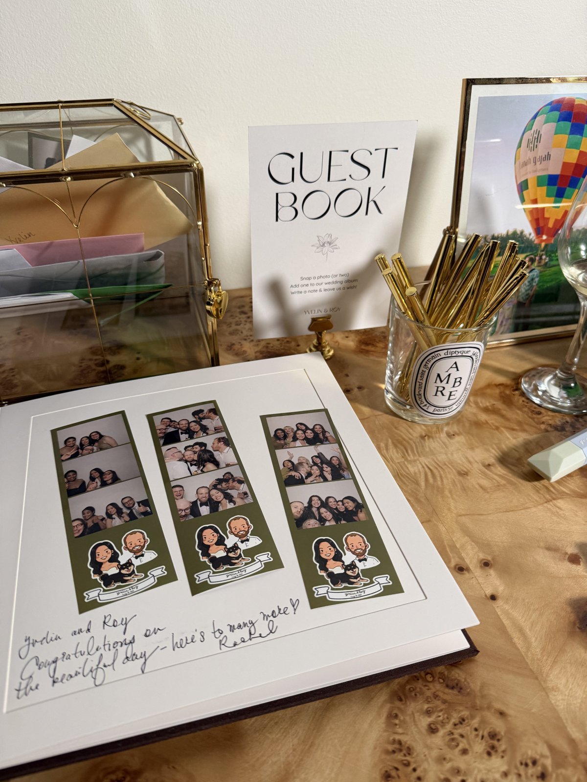 Wedding photo strips displayed in a guest book beside gold pens